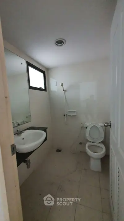 Compact bathroom with shower, sink, and toilet in a minimalist design.
