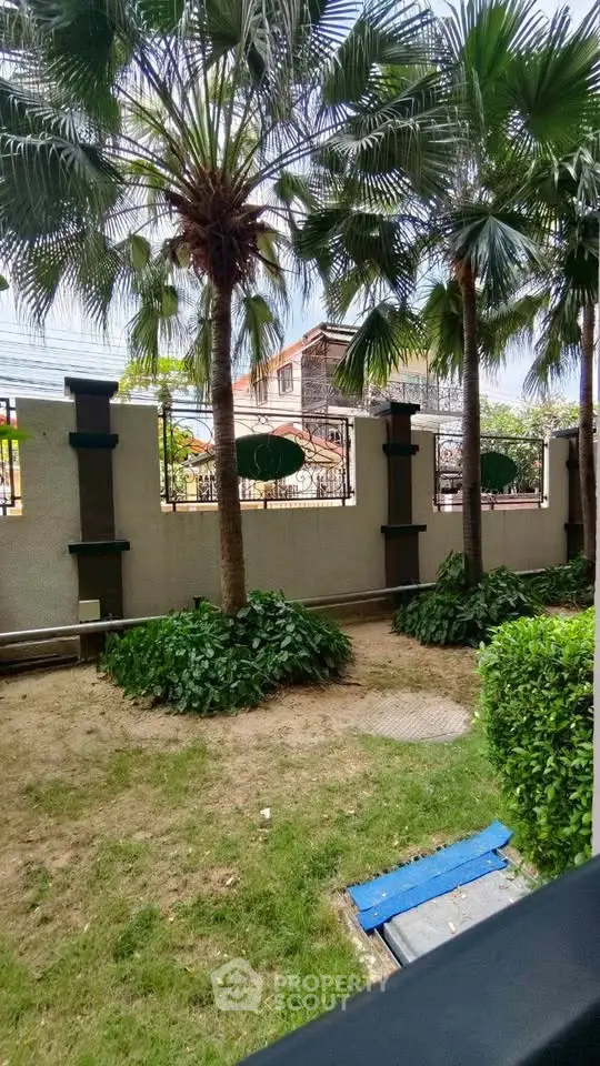 Charming garden view with lush greenery and palm trees in a serene residential setting.