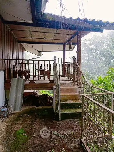 Charming rustic porch with metal railing and lush greenery, perfect for serene outdoor relaxation.