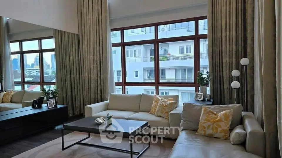 Spacious living room with large windows and modern decor in urban apartment.