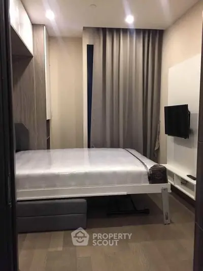 Cozy modern bedroom with sleek design and wall-mounted TV, perfect for urban living.