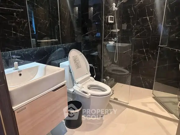 Luxurious modern bathroom with sleek black marble tiles and elegant fixtures.