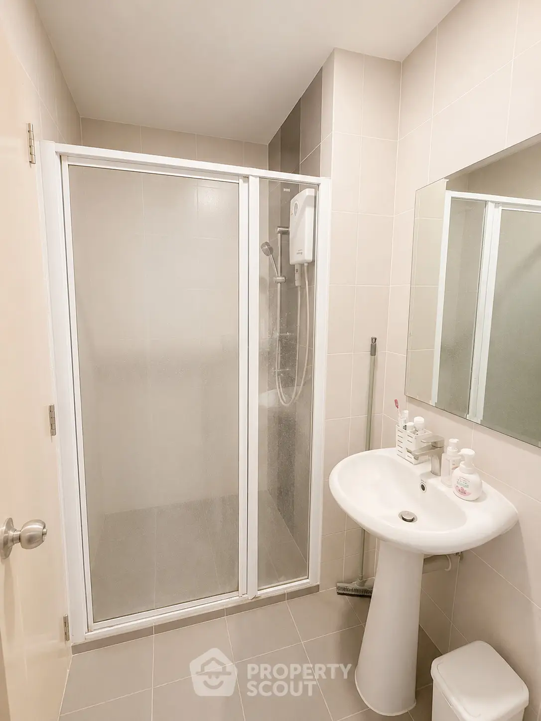 Modern bathroom with sleek shower enclosure and pedestal sink in neutral tones.
