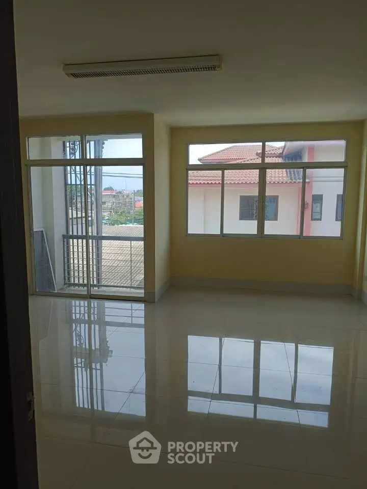 Spacious room with large windows offering ample natural light and a view of neighboring buildings.