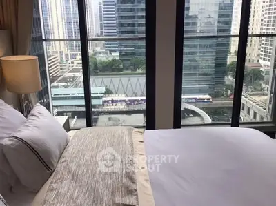 Luxurious bedroom with stunning city view through floor-to-ceiling windows in a high-rise apartment.