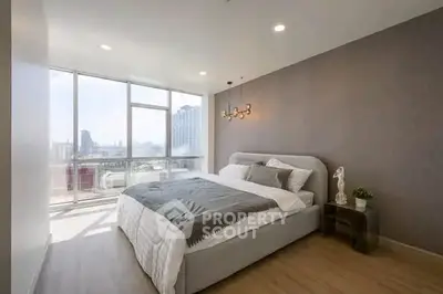 Spacious modern bedroom with large windows and city view, featuring elegant decor and ample natural light.