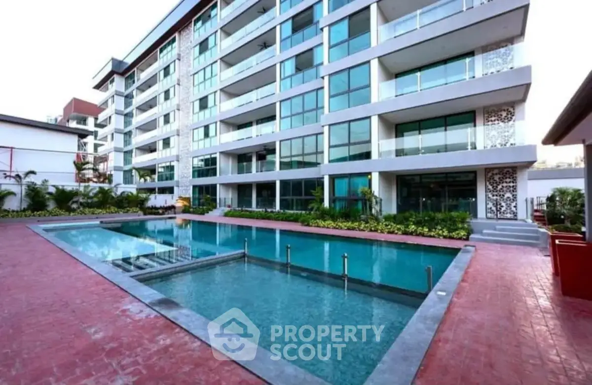 Modern apartment building with a luxurious pool and spacious balconies.