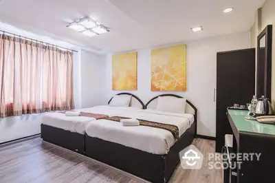 Spacious and modern bedroom with twin beds, elegant decor, and ample lighting, perfect for a comfortable living experience.