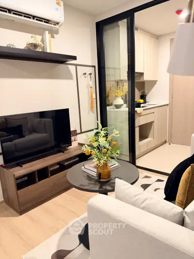 Modern living room with stylish decor and open kitchen layout, featuring a cozy seating area and sleek appliances.