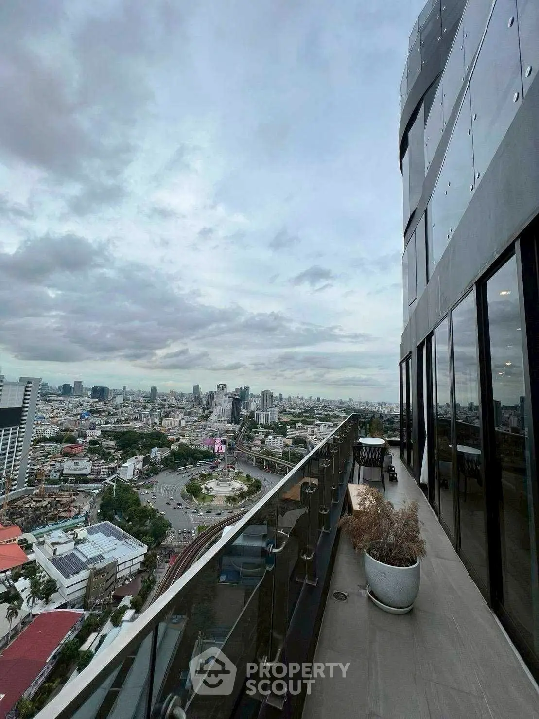 Stunning cityscape view from modern high-rise balcony with glass railing.