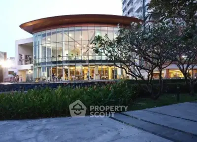 Stunning modern building with glass facade and lush landscaping, perfect for luxury living.
