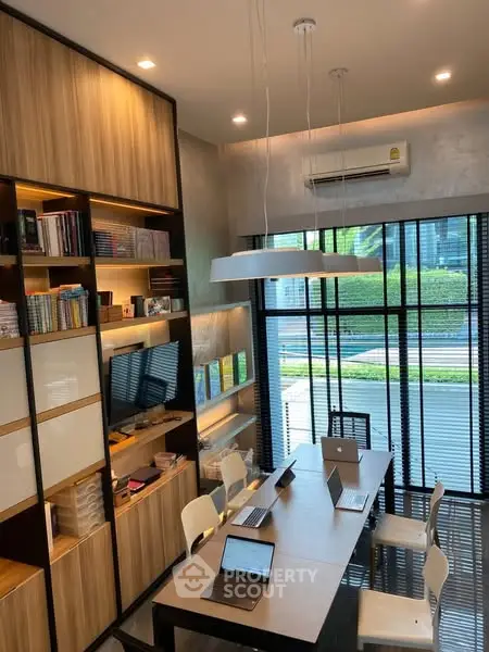 Modern study room with large window, built-in shelves, and sleek table setup.