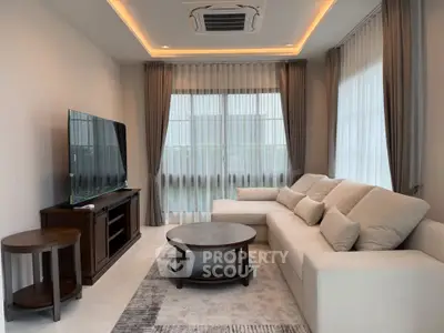 Modern living room with cozy sofa and large TV, featuring elegant curtains and stylish lighting.
