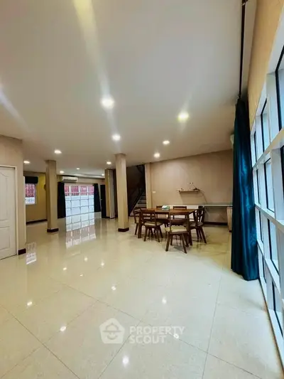 Spacious open-plan living area with elegant dining set and large windows for natural light.