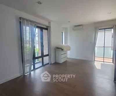 Spacious modern living room with large windows and balcony access in a bright apartment.