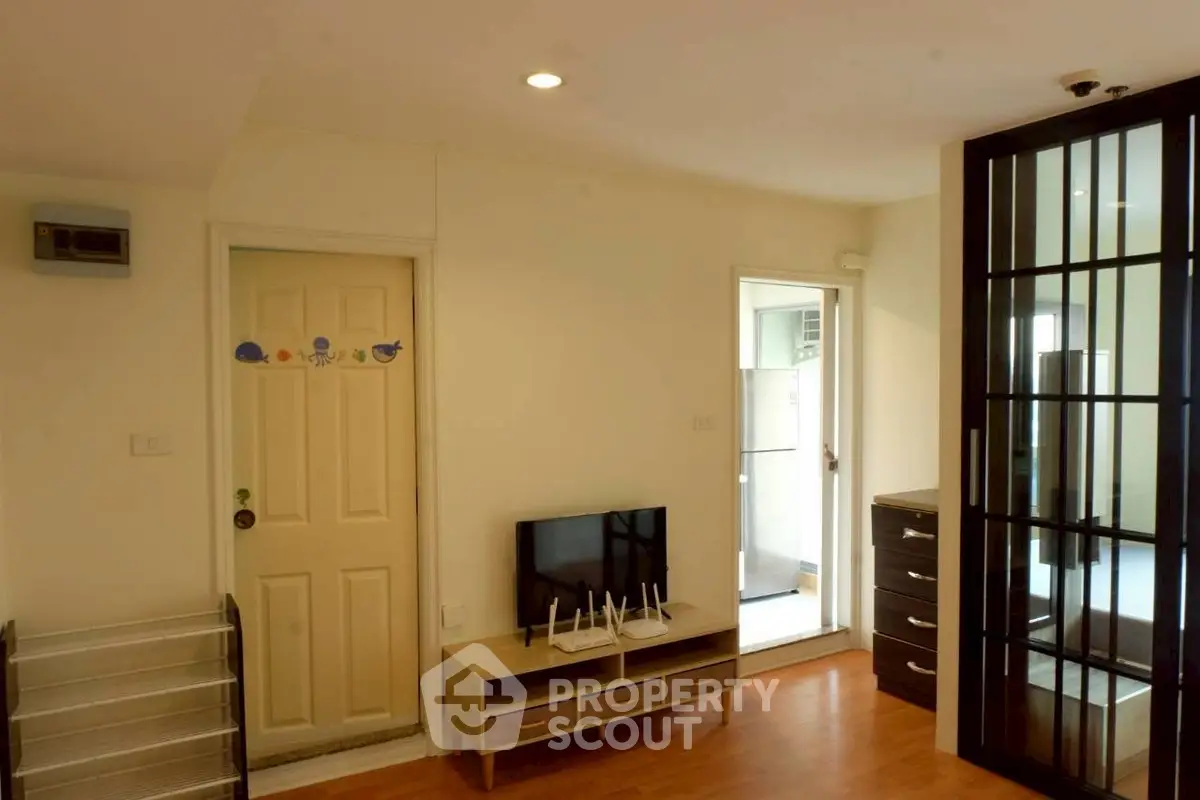 Modern living room with sleek furniture and open layout, featuring a stylish TV stand and glass partition.