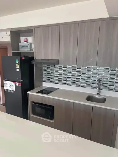 Modern kitchen with sleek cabinetry, built-in appliances, and stylish backsplash in a contemporary apartment.