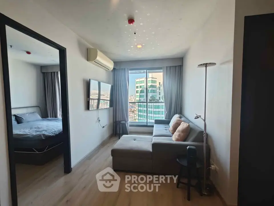 Modern living room with city view, cozy sofa, and adjacent bedroom in a stylish apartment.