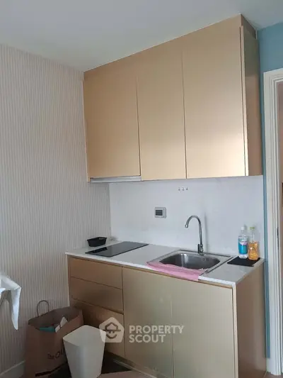 Modern compact kitchen with sleek gold cabinets and integrated appliances