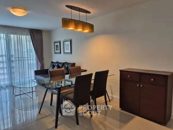 Modern dining area with glass table and elegant lighting in stylish apartment.