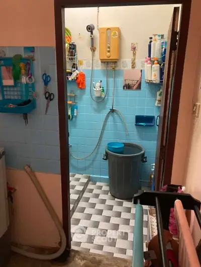 Compact bathroom with blue tiles and essential amenities, featuring a shower and storage solutions.