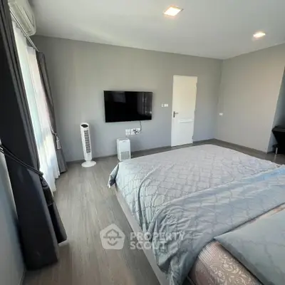 Modern bedroom with sleek design, featuring a wall-mounted TV and stylish gray bedding.