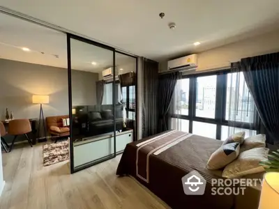 Modern bedroom with sliding glass doors and city view, featuring stylish decor and ample natural light.