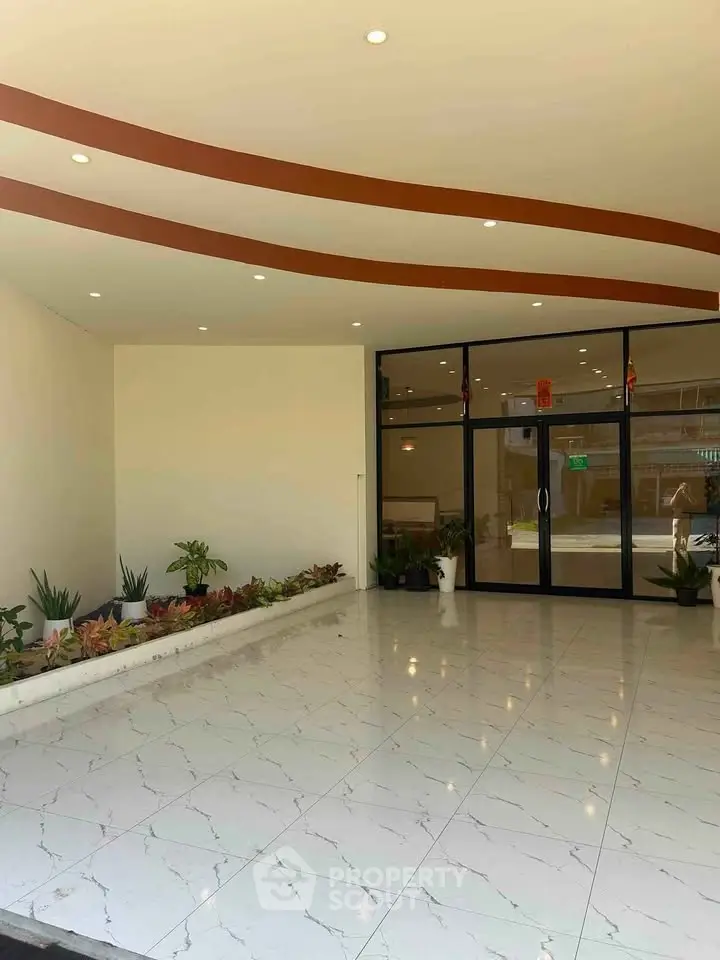 Elegant building entrance with modern design and polished marble flooring, featuring decorative plants for a welcoming ambiance.