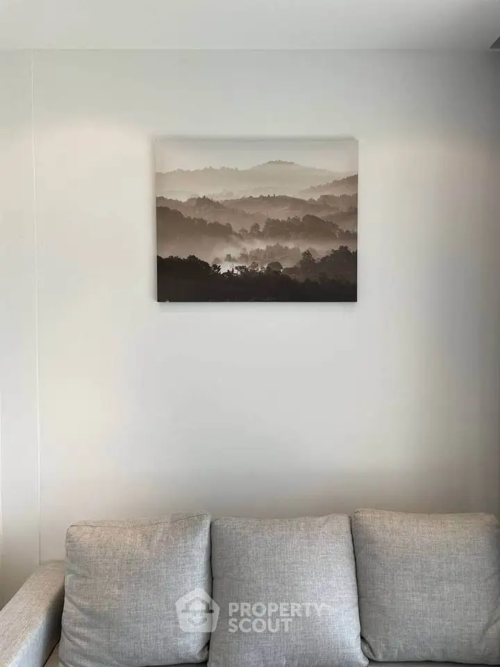Cozy living room with a stylish gray sofa and serene landscape artwork.