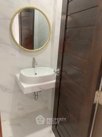 Modern bathroom with round mirror and sleek sink in a stylish real estate property.