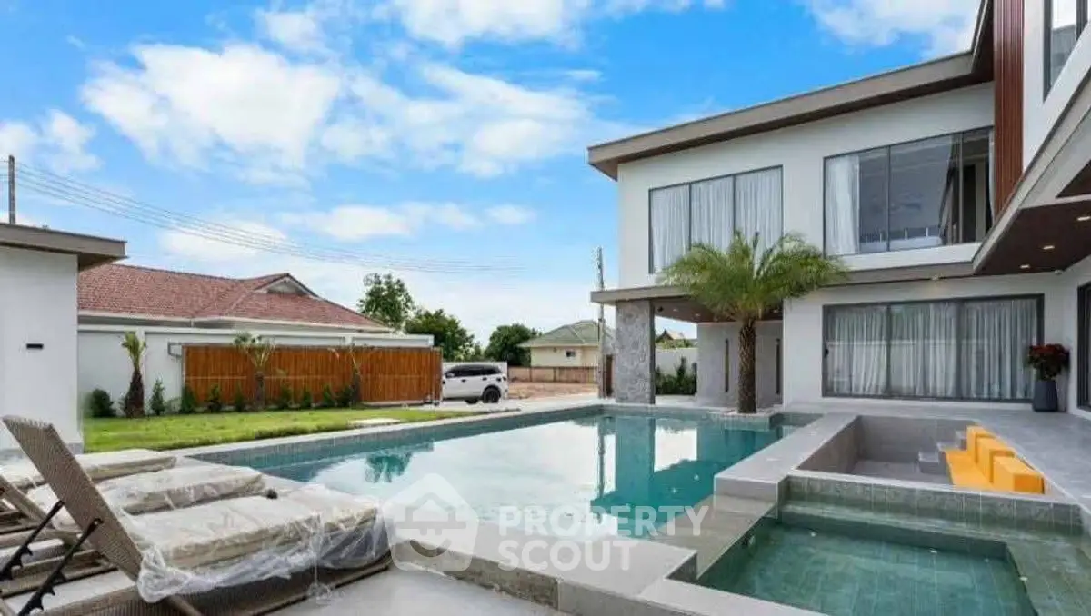 Luxurious modern home with stunning pool and outdoor seating area.