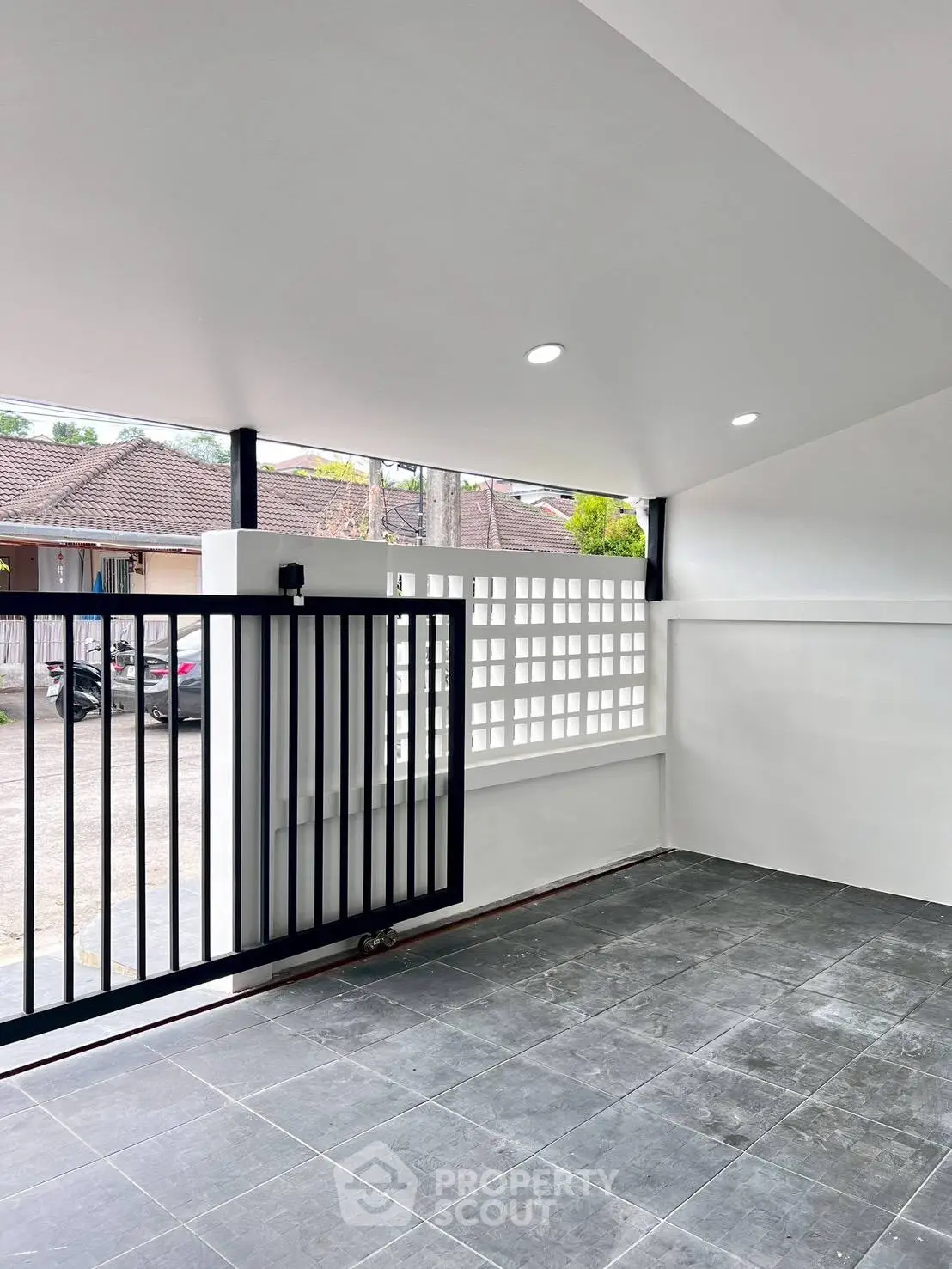 Modern covered parking area with sleek black gate and tiled flooring