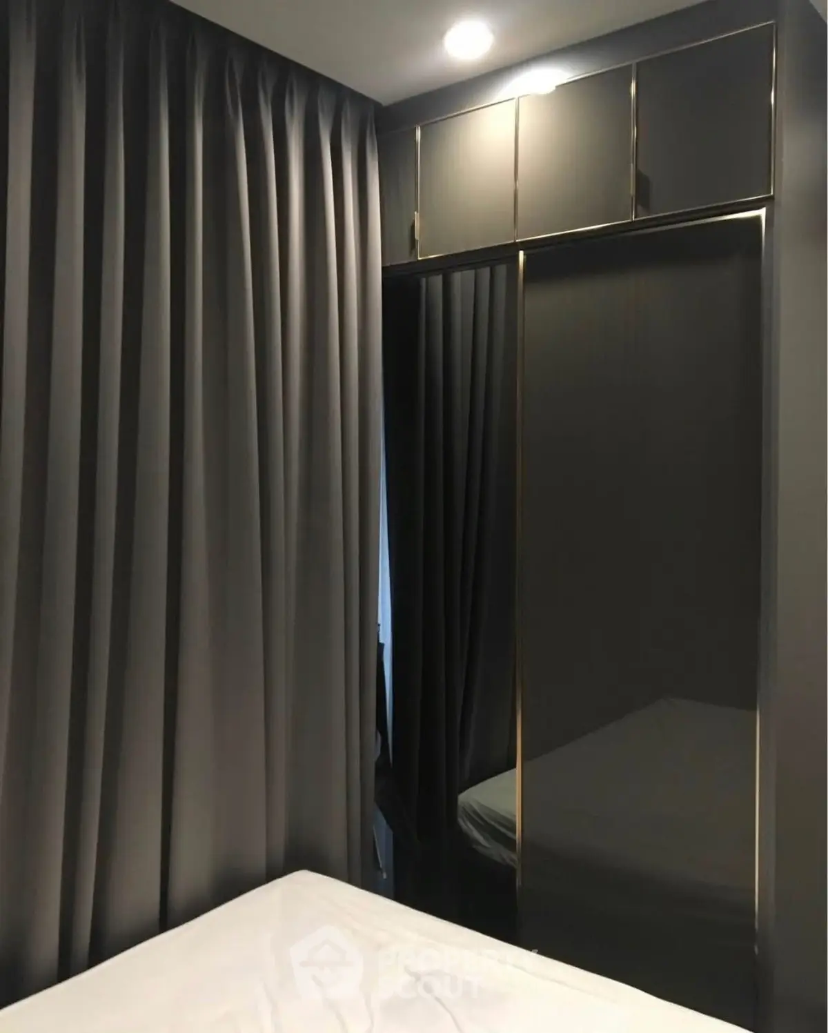 Modern bedroom with sleek mirrored wardrobe and elegant curtains