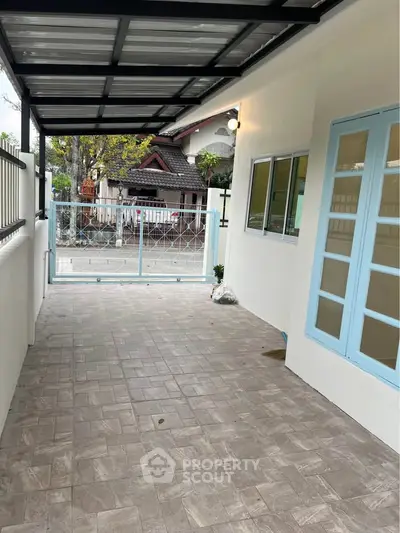 Charming covered patio with tiled flooring and blue French doors, perfect for outdoor relaxation.