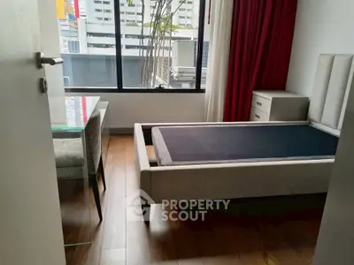 Modern bedroom with sleek design and large window offering city views.