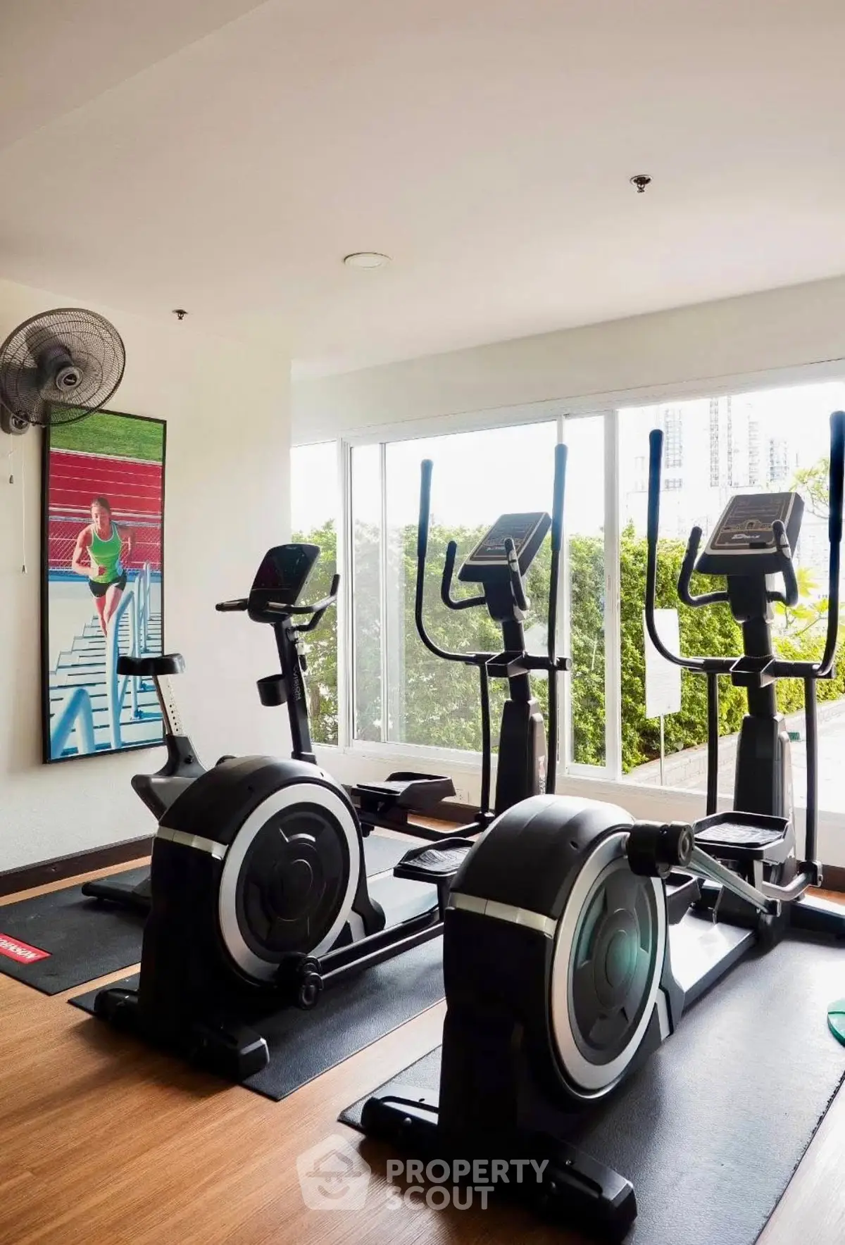 Modern gym with exercise bikes and large windows offering a lush green view, perfect for fitness enthusiasts.