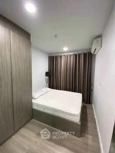 Modern bedroom with sleek wooden wardrobe and air conditioning in a cozy apartment.