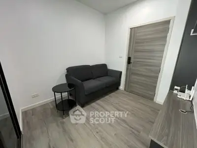 Modern minimalist living room with sleek gray sofa and stylish wooden flooring.
