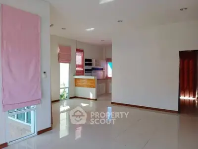 Bright and spacious living area with modern kitchen and large windows.