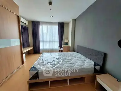 Spacious bedroom with modern furnishings and large window for natural light.