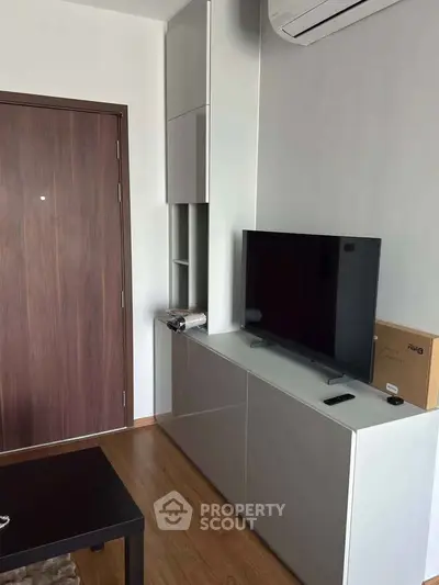 Modern living room with sleek TV unit and air conditioning, showcasing minimalist design and functionality.