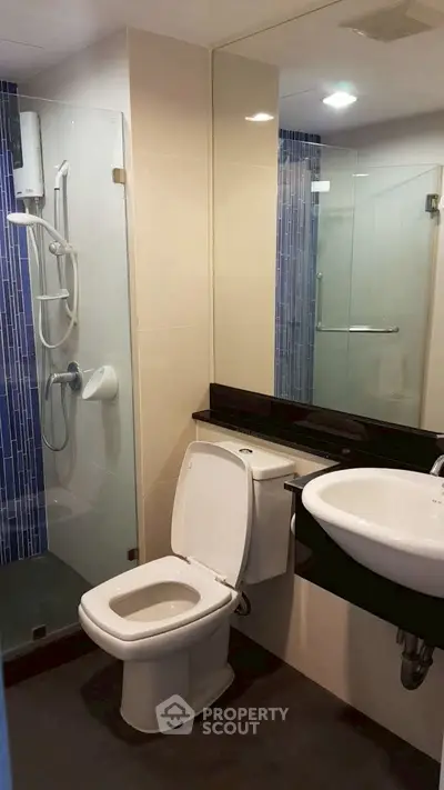 Modern bathroom with glass shower and sleek fixtures in a contemporary apartment.