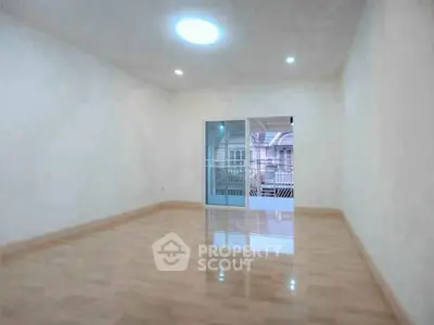Spacious empty room with polished wooden floors and large window for natural light.