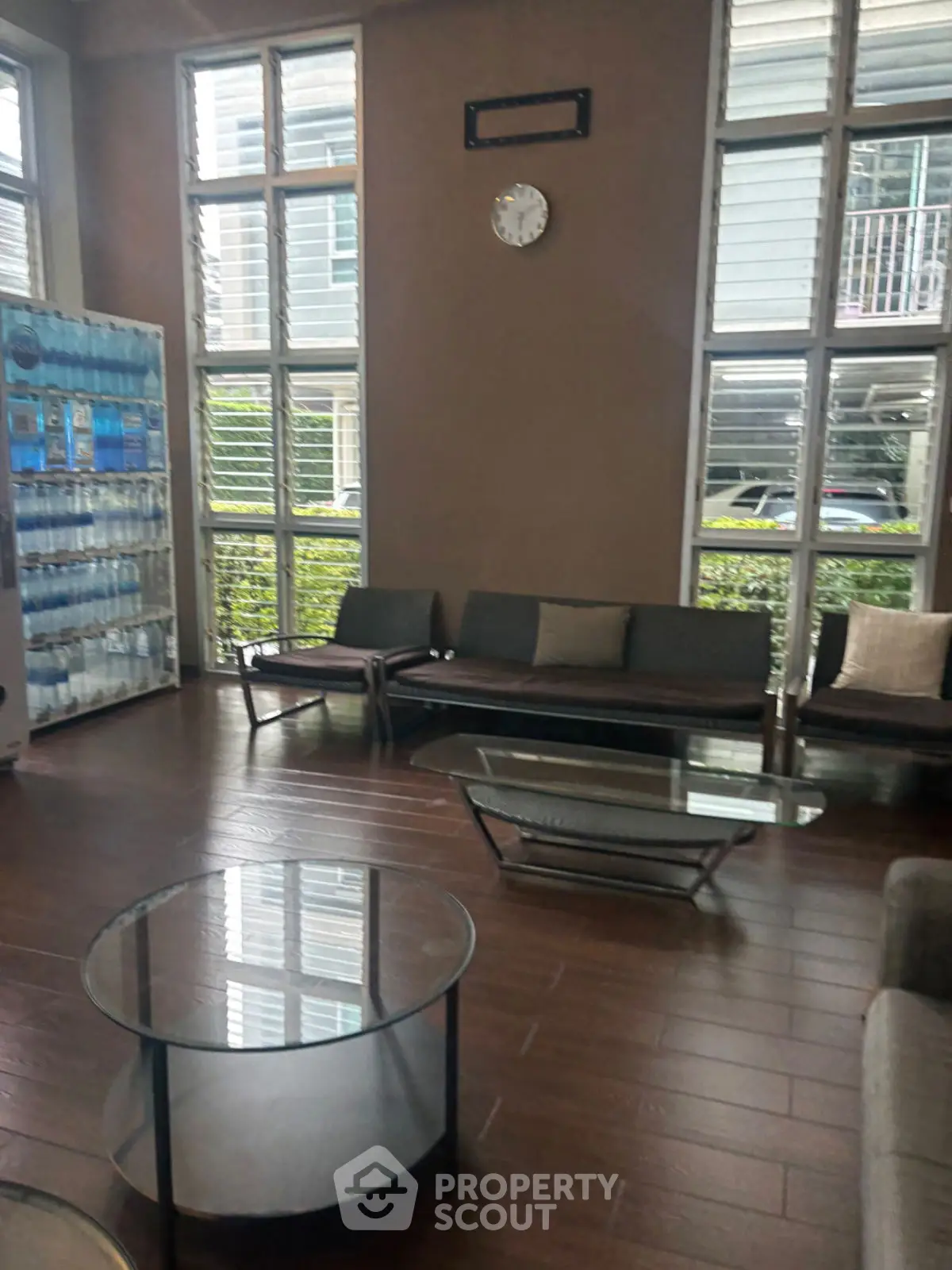 Modern waiting area with glass tables and large windows in a stylish building.