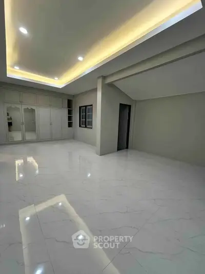 Spacious modern room with sleek marble flooring and built-in wardrobe, perfect for luxury living.