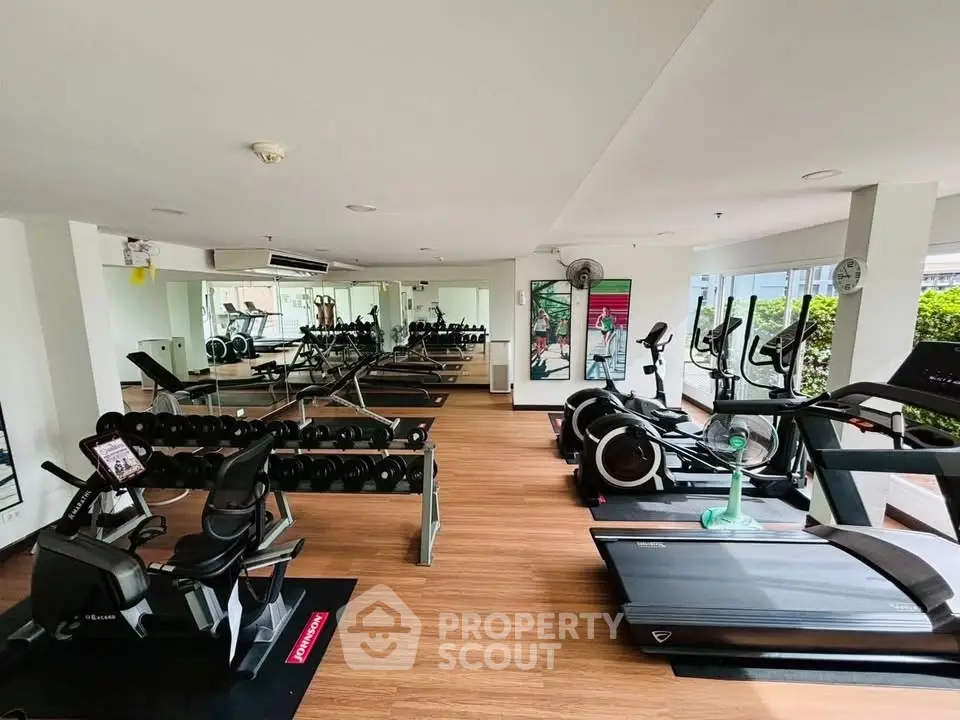 Spacious modern gym with state-of-the-art equipment and mirrored walls in a luxury apartment complex.