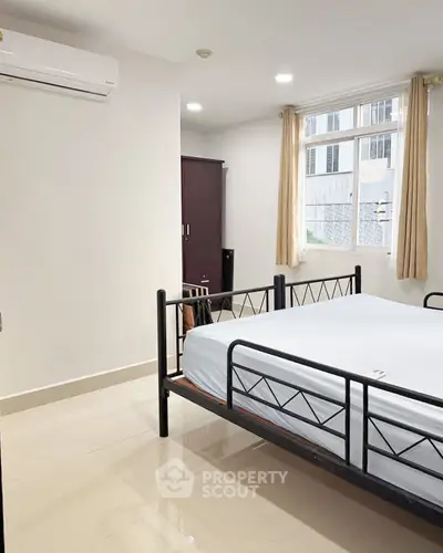 Spacious bedroom with modern furnishings and large window for natural light.