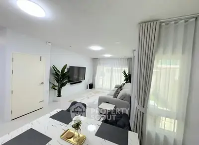 Modern living room with elegant decor and natural light, featuring a cozy seating area and stylish dining space.