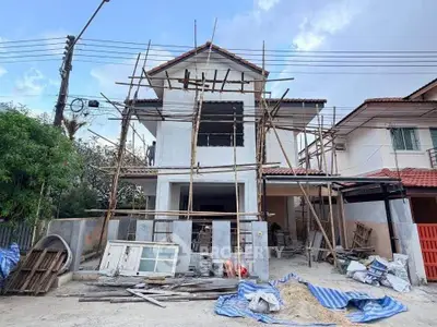 Under-construction two-story house with scaffolding and building materials.