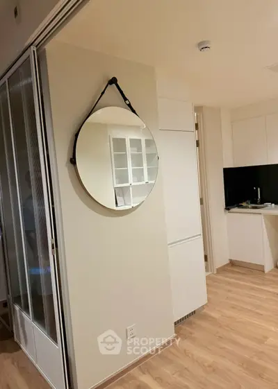 Modern apartment interior with stylish round mirror and sleek kitchen design.